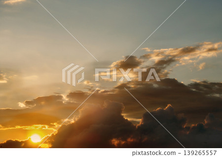 Dramatic Golden Sunset Clouds on Dark Blue Sky. Breathtaking high-contrast sky at sunset. Golden light illuminates dark storm clouds against a deep blue dusk sky. 139265557