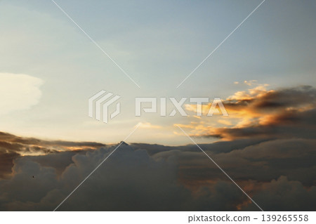 Dramatic Golden Sunset Clouds on Dark Blue Sky. Breathtaking high-contrast sky at sunset. Golden light illuminates dark storm clouds against a deep blue dusk sky. 139265558