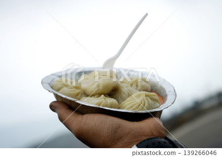 Hand holding a plate of fresh steamed momos during a travel break 139266046