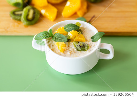 Healthy oatmeal breakfast with kiwi orange and fresh green mint Healthy oatmeal breakfast with kiwi orange and fresh green mint 139266504