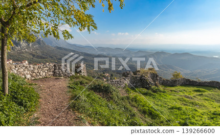 Rural countryside Albania. Mountain range with small village in the valley with sunset vibrant sky Rural countryside Albania. Mountain range with small village in the valley with sunset vibrant sky 139266600
