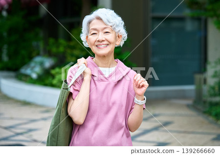 一位背著手提包、面帶微笑的老婦人。 一位背著手提包、面帶微笑的老婦人。 139266660