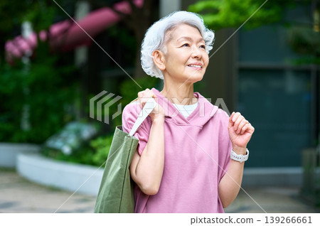 一位提著手提包的老婦人抬頭望著天空。 一位提著手提包的老婦人抬頭望著天空。 139266661
