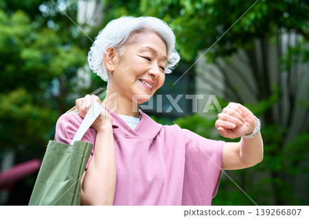 A senior woman happily carrying a tote bag. 139266807