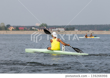 Rear view athlete kayaker paddling on open water Rear view athlete kayaker paddling on open water 139266998