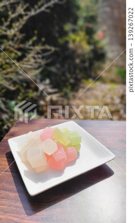 Colorful Japanese sweets, including amber candy, served on a white plate for outdoor enjoyment. Colorful Japanese sweets, including amber candy, served on a white plate for outdoor enjoyment. 139267022
