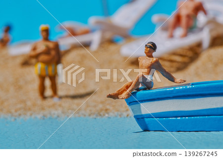 a miniature man leaning on a blue boat a miniature man leaning on a blue boat 139267245