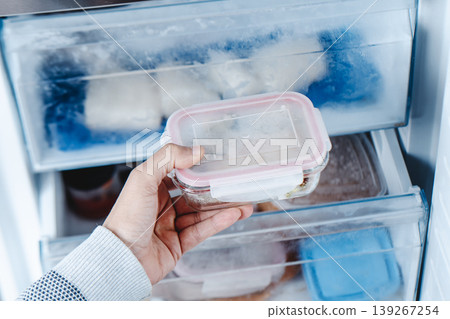 a man taking a container from the freezer a man taking a container from the freezer 139267254