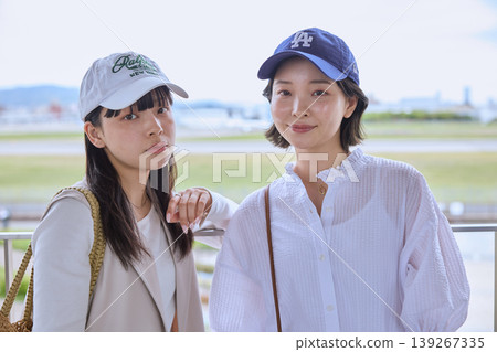 A portrait of two young women wearing caps outdoors in the summer – friends out and about. A portrait of two young women wearing caps outdoors in the summer – friends out and about. 139267335