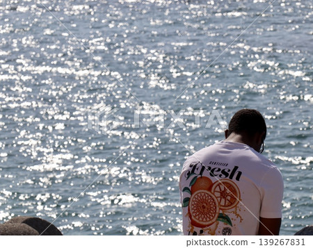 A man's back as he gazes at the sea, lost in thought. (Person Focus | Blog, Self-Improvement, Mental Health, Advertising, Business Articles) 139267831