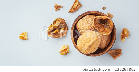 Roasted walnuts in wooden bowl with cracked walnuts on table, flat lay Roasted walnuts in wooden bowl with cracked walnuts on table, flat lay 139267892