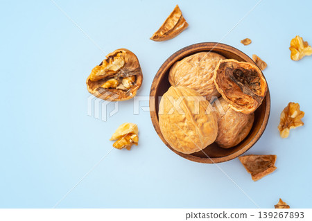 Walnuts in wooden bowl with cracked walnuts on blue background, healty snack, top view Walnuts in wooden bowl with cracked walnuts on blue background, healty snack, top view 139267893