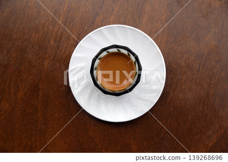 Glass cup of fresh espresso coffee with thick crema on a dark table in a cafe Glass cup of fresh espresso coffee with thick crema on a dark table in a cafe 139268696