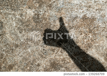 Hand shadow showing thumbs up gesture on a textured gray cement surface Hand shadow showing thumbs up gesture on a textured gray cement surface 139268709