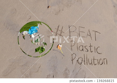 Earth shape with plastic waste texture beside handwritten message “#BEAT Plastic Pollution” on beach sand, representing global awareness of environmental pollution 139268815