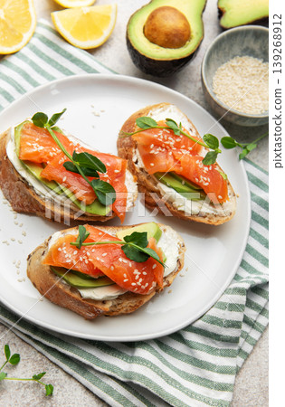 Preparing avocado salmon toasts with sesame seeds and lemon Preparing avocado salmon toasts with sesame seeds and lemon 139268912