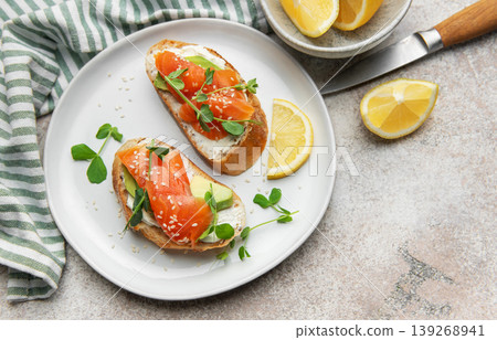Salmon avocado toasts with microgreens and lemon 139268941
