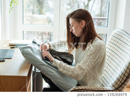 Woman unboxing package after online shopping at home Woman unboxing package after online shopping at home 139268979