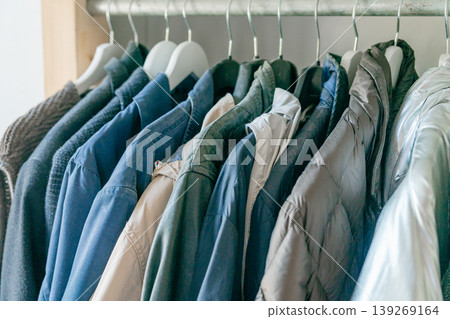 Mens clothing neatly arranged on hangers. Clean and minimal wardrobe interior. 139269164