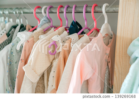 Soft pastel baby clothes hanging on rack. Children wardrobe organization and gentle lifestyle concept. Soft pastel baby clothes hanging on rack. Children wardrobe organization and gentle lifestyle concept. 139269168