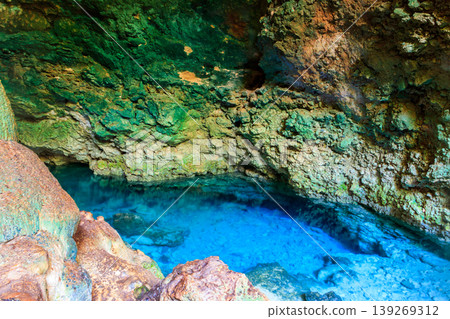 View of beautiful natural pool of crystal clear water formed in a rocky cave with stalagmites and stalagmites. Kuza cave in Zanzibar, Tanzania View of beautiful natural pool of crystal clear water formed in a rocky cave with stalagmites and stalagmites. Kuza cave in Zanzibar, Tanzania 139269312