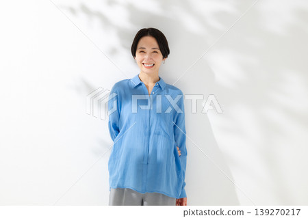一位微笑的女人站在透過樹梢的陽光下 一位微笑的女人站在透過樹梢的陽光下 139270217