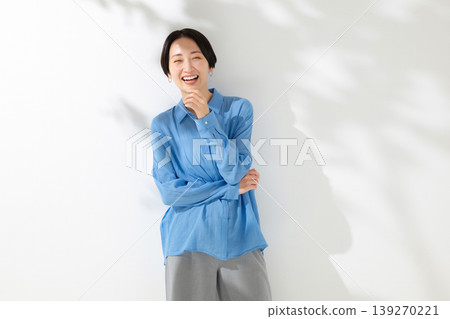 一位微笑的女人站在透過樹梢的陽光下 一位微笑的女人站在透過樹梢的陽光下 139270221