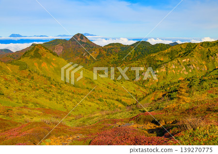 View from the watershed in autumn: Mt. Kasagatake in autumn colors and the Northern Alps mountain range floating in a sea of clouds. View from the watershed in autumn: Mt. Kasagatake in autumn colors and the Northern Alps mountain range floating in a sea of clouds. 139270775