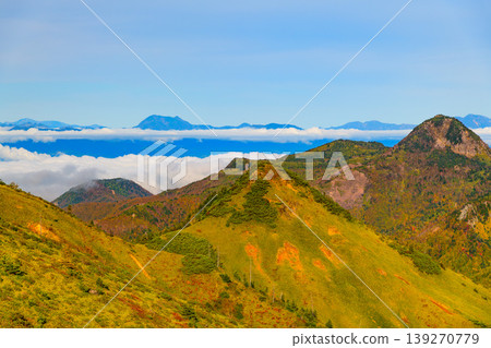 View from the watershed in autumn: Mt. Kasagatake in autumn colors and the Northern Alps mountain range floating in a sea of clouds. View from the watershed in autumn: Mt. Kasagatake in autumn colors and the Northern Alps mountain range floating in a sea of clouds. 139270779