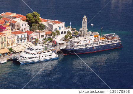Cruise ship in Symi harbor with waterfront buildings on sunny clear summer day Cruise ship in Symi harbor with waterfront buildings on sunny clear summer day 139270898