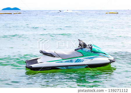 A blue sea with jet skis floating on it 139271112