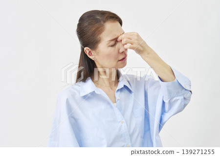 A woman holding the corners of her eyes against a white background A woman holding the corners of her eyes against a white background 139271255