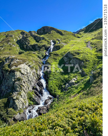Mountain waterfall on green slope in Les Contamines-Montjoie, France Mountain waterfall on green slope in Les Contamines-Montjoie, France 139271518