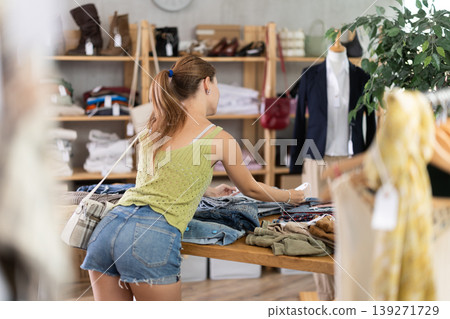 Young woman choosing jeans in clothing store Young woman choosing jeans in clothing store 139271729