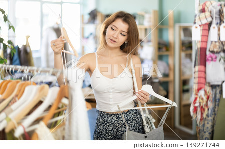 Young girl choosing summer dress in clothing store Young girl choosing summer dress in clothing store 139271744