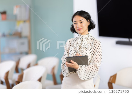 Female coach with clipboard look at camera posing in classroom Female coach with clipboard look at camera posing in classroom 139271790