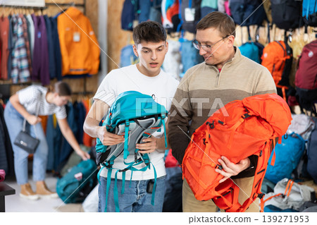 Father and son choose a backpack for hike together in store that sells sports equipment 139271953