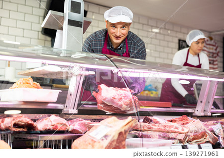 Adult man puts pork ribs in showcase 139271961