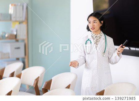 Female doctor gives lecture in classroom while holding remote control 139271985