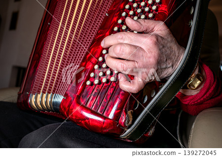 Person playing the accordion, a vintage musical instrument 139272045