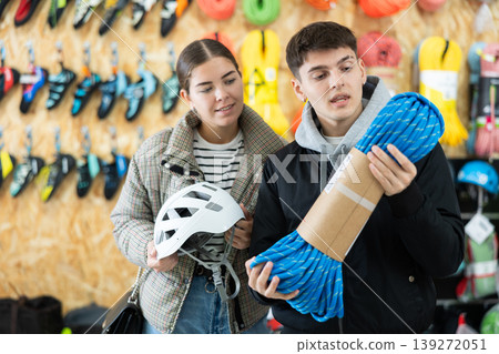 Guy and girl view rope cable for climbing and evaluate its thickness Guy and girl view rope cable for climbing and evaluate its thickness 139272051
