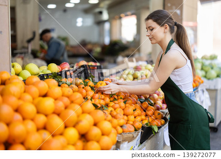 Woman seller laying oranges on counter 139272077