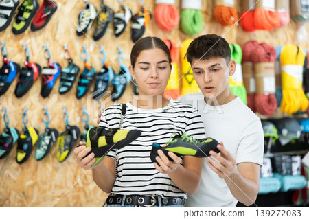 Girl and her boyfriend choose climbing shoes together in sports store Girl and her boyfriend choose climbing shoes together in sports store 139272083