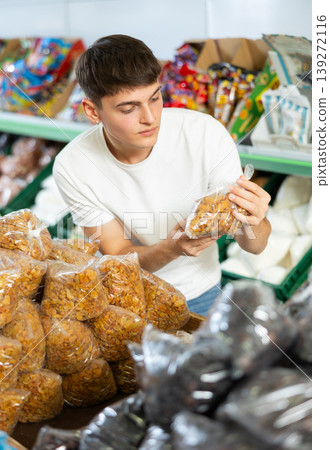 Interested guy choosing packaged raisins on counter in grocery store Interested guy choosing packaged raisins on counter in grocery store 139272116