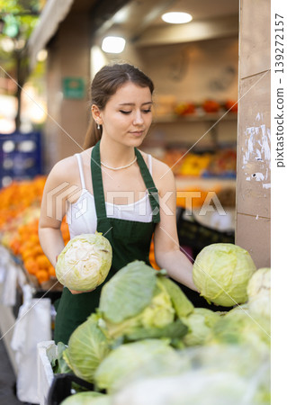 saleswoman lays out large cabbage on the counter saleswoman lays out large cabbage on the counter 139272157