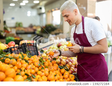 Guy shop seller puts tangerine goods on display case Guy shop seller puts tangerine goods on display case 139272164