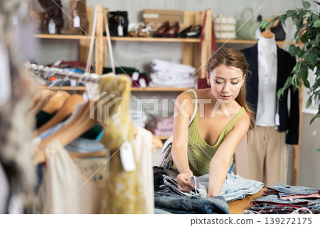 Young woman scanning barcode of jeans in store Young woman scanning barcode of jeans in store 139272175