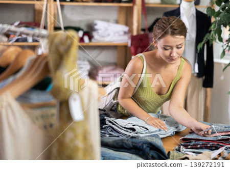 Woman shopping in clothing department, buying denim pantalones Woman shopping in clothing department, buying denim pantalones 139272191