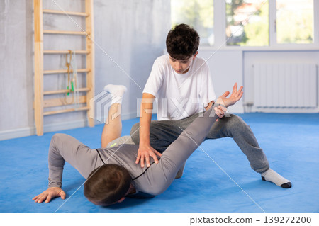 Father teaching his son wrestling or self-defense techniques in gym 139272200