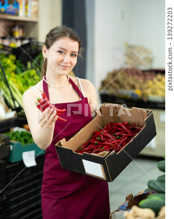 Female seller holding a box of chili peppers Female seller holding a box of chili peppers 139272203